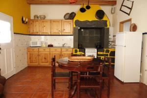 a kitchen with a table with chairs and a refrigerator at Casa capelinhos in Capelo