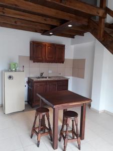 uma cozinha com uma mesa de madeira e 2 bancos de bar em Clima Serrano em Merlo