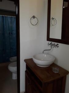 La salle de bains est pourvue d'un lavabo, de toilettes et d'un miroir. dans l'établissement Clima Serrano, à Merlo