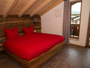 a red bed with red pillows in a room at Haus im Moos - Chiemgau Karte in Inzell