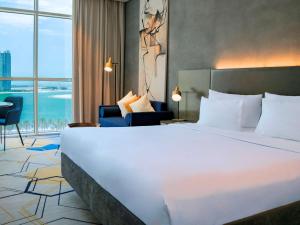 a hotel room with a large bed and a large window at Pullman Sharjah in Sharjah