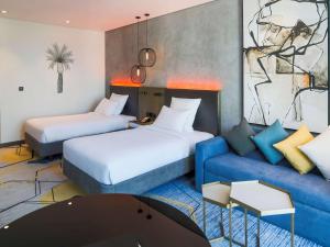 a hotel room with two beds and a couch at Pullman Sharjah in Sharjah
