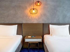 two beds in a room with a table between them at Pullman Sharjah in Sharjah