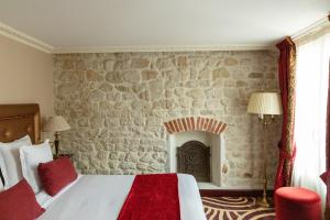 Hotel Du Beaumont في باريس: غرفة نوم بسرير وجدار حجري
