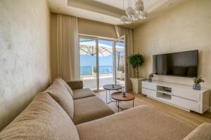 a living room with a couch and a television at Petra's Beachfront Penthouse in Sveti Stefan