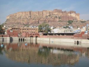 eine Stadt mit einem Berg im Hintergrund und einem Wasserkörper in der Unterkunft Jee Ri Haveli in Jodhpur