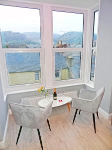 a living room with two chairs and a table and windows at Sea Nest Apartment by Seaside Llandudno in Llandudno