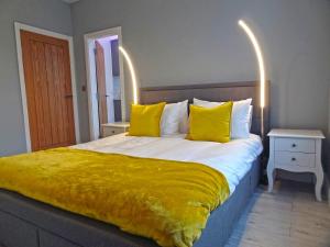 a bedroom with a large bed with yellow pillows at Sea Nest Apartment by Seaside Llandudno in Llandudno