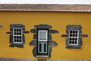 un edificio amarillo con dos ventanas. en Casa capelinhos, en Capelo