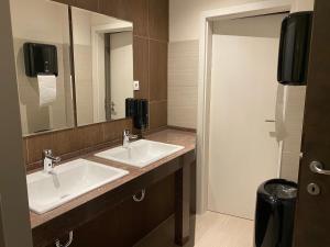 a bathroom with two sinks and a mirror at Hotel-Jakobslust in Grünstadt