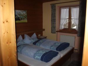 a bedroom with a bed with blue sheets and a window at Gästehaus Kress - Chiemgau Karte in Inzell