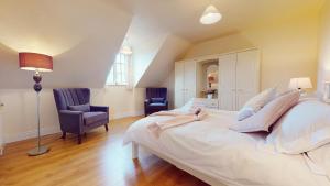 una camera da letto con un grande letto bianco e due sedie di Ross Beach Family Farmhouse B&B a Killala