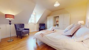 a bedroom with a large white bed and two chairs at Ross Beach Family Farmhouse B&B in Killala
