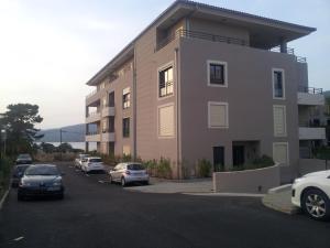 a large building with cars parked in a parking lot at Marina d'Oro in Propriano