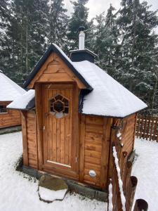 una casa de perros de madera con techo cubierto de nieve en U Justina na břehu en Velké Karlovice