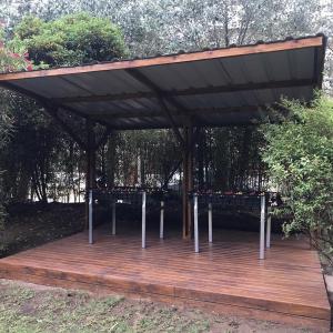 een houten terras met een paviljoen in een park bij Rey del Bosque Apart - Hotel & Spa in Valeria del Mar