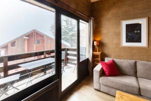 - un salon avec un canapé et une grande fenêtre dans l'établissement L'Ecrin des 2 Alpes, à Les Deux Alpes