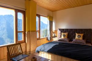 a bedroom with a bed in a room with windows at The Hosteller Shoja, Jibhi in Jibhi