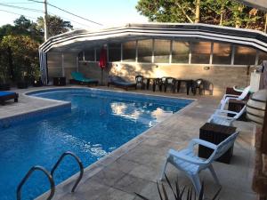 una piscina con sillas y mesas junto a un edificio en Rey del Bosque Apart - Hotel & Spa en Valeria del Mar