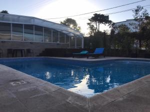 een zwembad met een bank naast een gebouw bij Rey del Bosque Apart - Hotel & Spa in Valeria del Mar