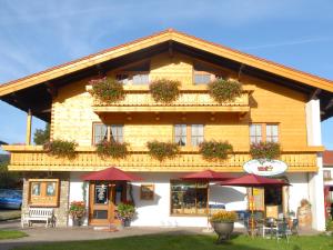 a large building with red umbrellas in front of it at Gasthof-Metzgerei Hirschbichler - Chiemgau Karte in Inzell