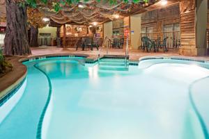 a swimming pool in a resort with tables and chairs at Holiday Inn Hotel & Suites Madison West, an IHG Hotel in Middleton