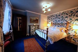 a bedroom with a bed and a wall of wallpaper at Plas Esgair in Llanbrynmair