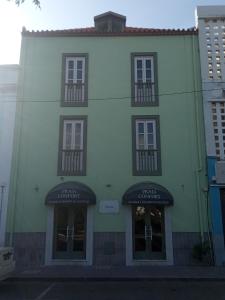 a large white building with two windows and two balconies at Hotel Praia Confort in Praia