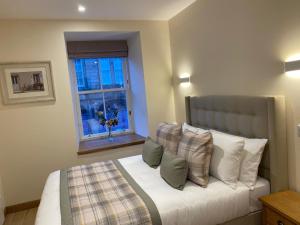 1 dormitorio con cama con almohadas y ventana en Waverley Inn Holiday Apartments en Inverness