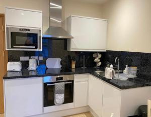 Una cocina con gabinetes blancos y encimeras negras. en Waverley Inn Holiday Apartments, en Inverness