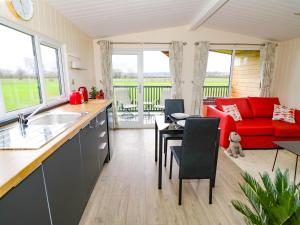 cocina y sala de estar con sofá rojo en Cotswold View 2, en Evesham