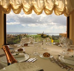 un tavolo con bicchieri da vino e una grande finestra di Grand Hotel Paradiso a Catanzaro Lido