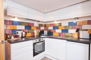 uma cozinha com armários brancos e azulejos coloridos na parede em Number 57 em Kegworth