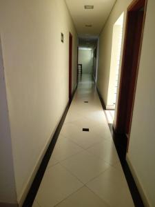 a hallway with a long corridor with white tiles on the floor at Hotel ZM Premium in Cosmópolis