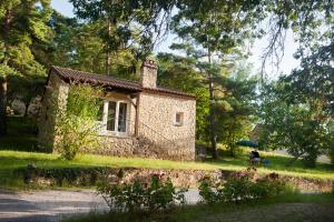 une petite maison en pierre au milieu d'un parc dans l'établissement Les gites de Sarlat, à Sarlat-la-Canéda