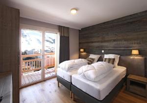 a bedroom with two beds and a large window at Les Chalets Grizzly in Les Deux Alpes