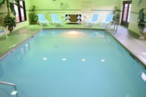 uma piscina num quarto de hotel com cadeiras e cadeiras azuis em Holiday Inn Express & Suites Pensacola West I-10, an IHG Hotel em Pensacola