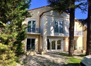 une grande maison blanche avec des arbres devant elle dans l'établissement Castel Mireio, à Cairanne