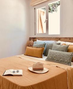 a hat and a book on top of a bed at Can Petit - Romantic & Cozy Villa in Sant Ferran de Ses Roques