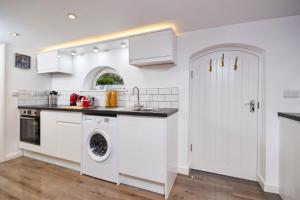a kitchen with white cabinets and a washer and dryer at The Hidden Gem in Kegworth