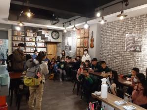 un grupo de personas sentadas en mesas en un restaurante en 清淨背包客棧-民權館Quiet Hostel - Minquan Inn, en Tainan