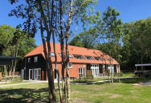 a large house with a red roof and trees at Hofstede Moesbosch I Kloeg Collection in Koudekerke