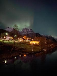 a night time view of a village with snow covered mountains at House on the lake in Bogen