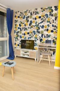 a living room with a tv and a floral wall at APPARTEMENT ENTRE GENÈVE ET CHAMONIX AU PIED DES MONTAGNES in Cluses