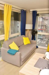 a living room with a couch with yellow and blue pillows at APPARTEMENT ENTRE GENÈVE ET CHAMONIX AU PIED DES MONTAGNES in Cluses