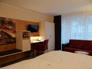 a hotel room with a bed and a desk and a couch at Höger's Hotel & Restaurant in Bad Essen
