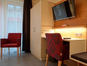 Habitación con escritorio y TV en la pared. en Höger's Hotel & Restaurant en Bad Essen