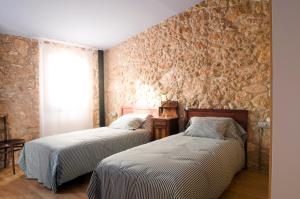 two beds in a room with a stone wall at Ca l'Helena in Castellet