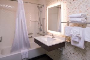 W białej łazience znajduje się umywalka i lustro. w obiekcie Holiday Inn Auburn-Finger Lakes Region, an IHG Hotel w mieście Auburn