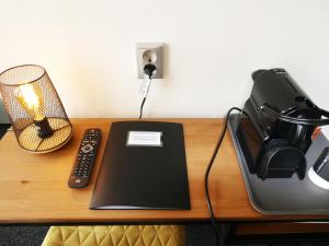 a desk with a laptop and a phone and a lamp at Hotel Café Restaurant De Posthoorn in Dokkum